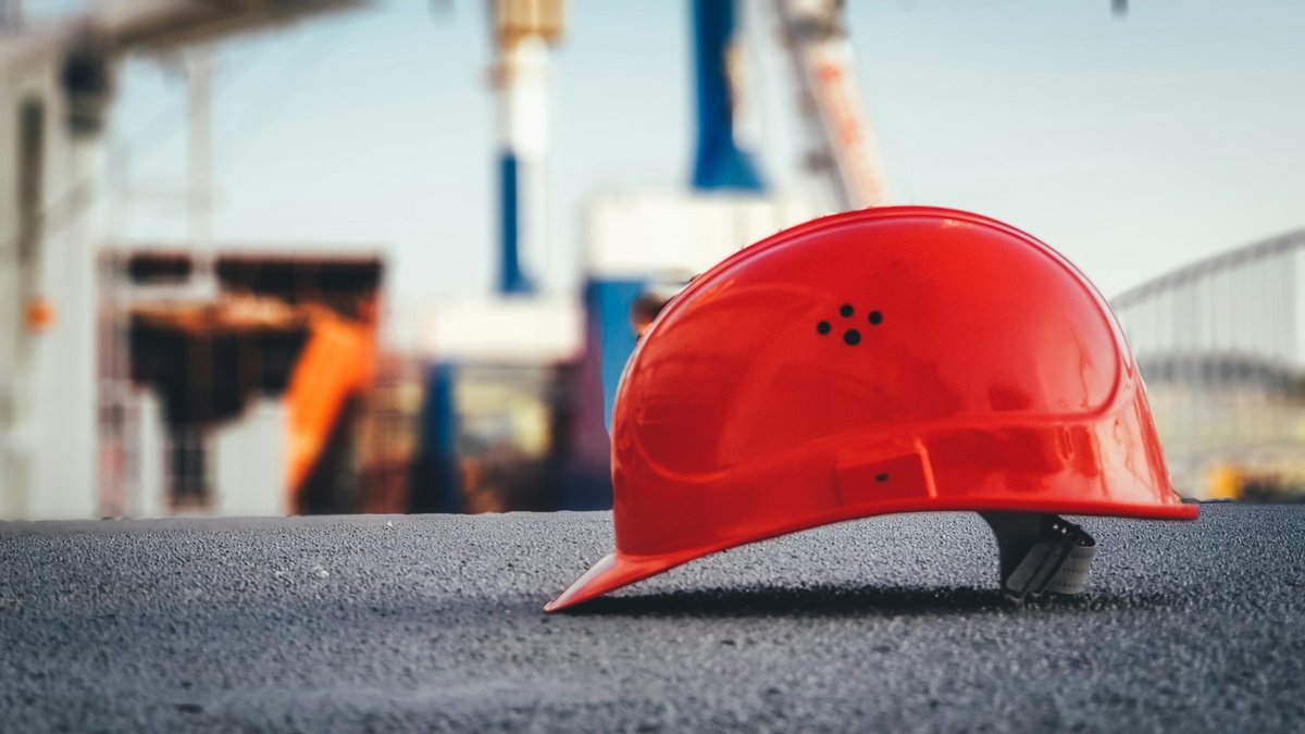 Casque de chantier rouge posé sur un trottoir